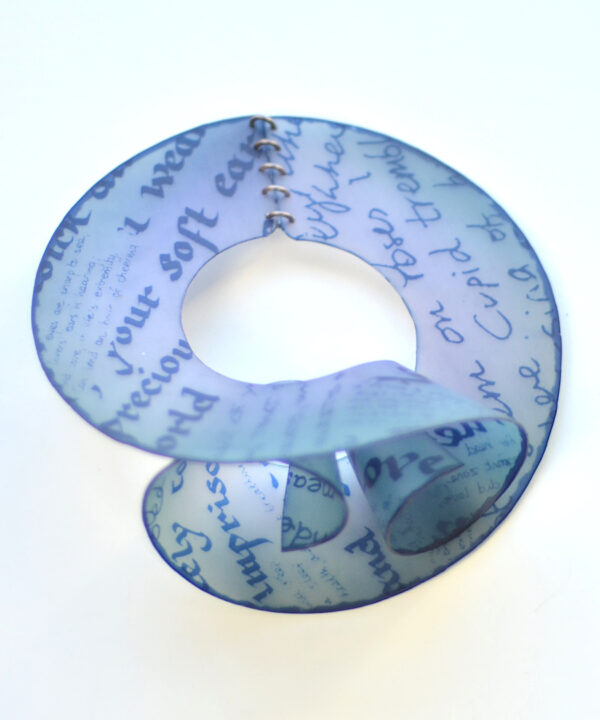 Collaged sections of hand written 19th century romantic poetry have been dyed into the nylon using a screen-printed resists to make this flexible nylon bracelet. This view shows the spiral terminals.